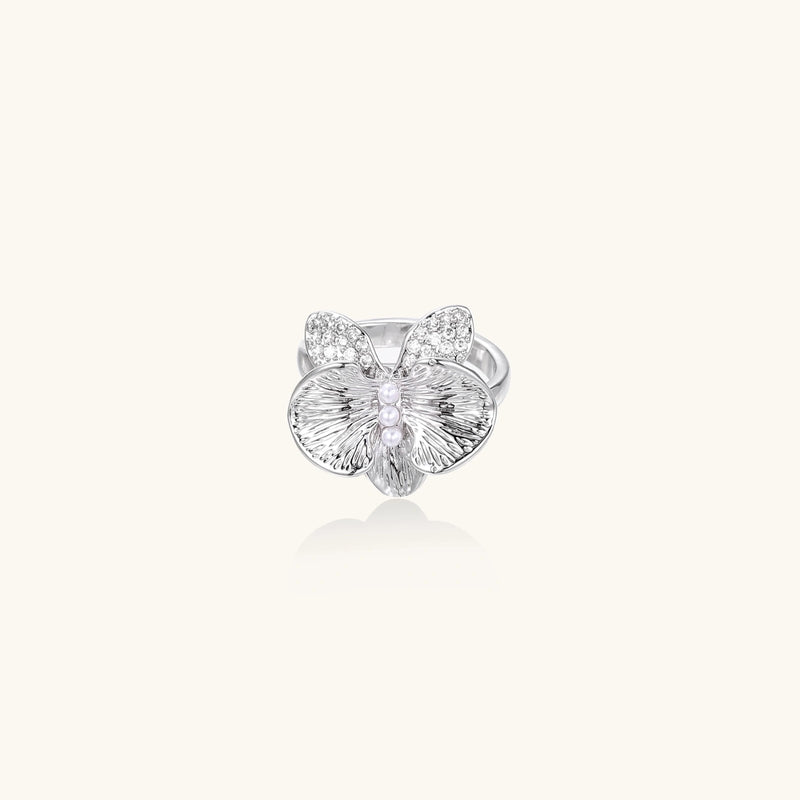 Silver-toned orchid ring with textured petals, pearl center accents, and sparkling zirconia stones on white background.